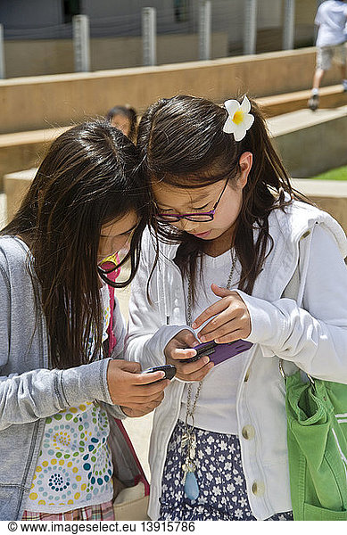 Preteen Girls Comparing Blogs on Cell Phones