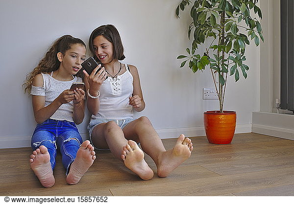 Preteen girls showing each other content on their mobile phones.
