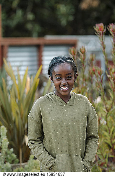 Pretty smiling black girl in a polka-dot hoodie by tall plants