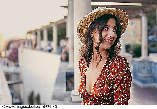 Pretty woman in a straw hat looking aside in a European town
