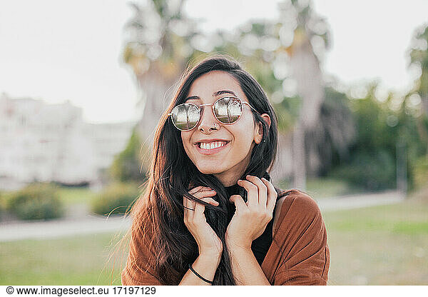 Pretty woman in sunglasses holding headphones and laughing