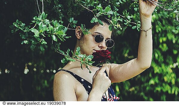 pretty young girl with a red rose among trees