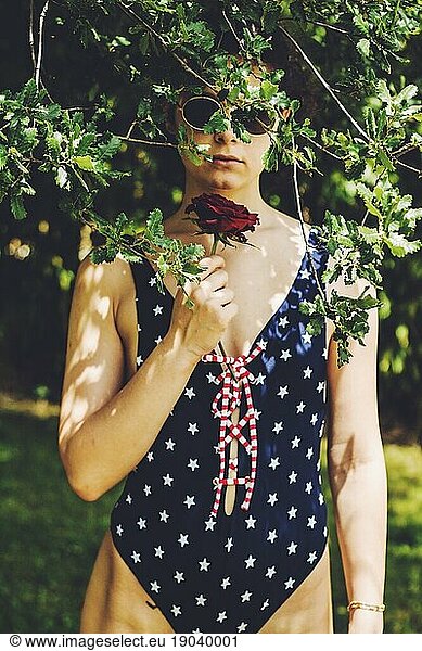 pretty young girl with a red rose sunglasses and blue swimsuit