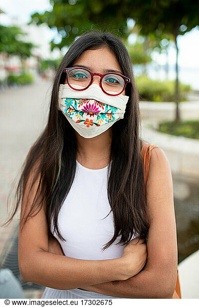 Pretty young woman smiling with facemask and glasses
