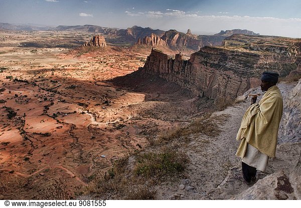 Priest looking off a rock ledge from the Daniel Korkor church in Tigray  Ethiopia.