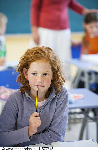Primary schoolgirl thinking in classroom