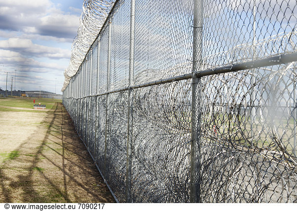 Prison fence and barbed wire at Correctional Facility. High security fencing. Close up.