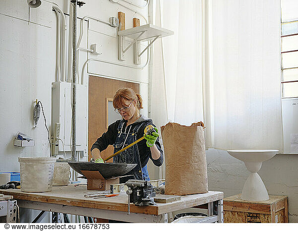 Professional female sculptor measuring her work in her studio