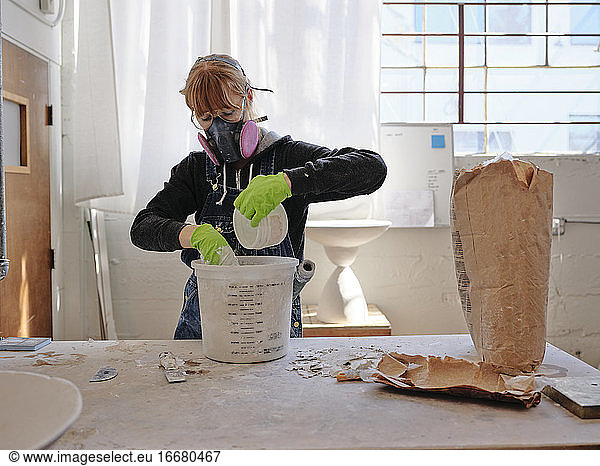 Professional female sculptor mixing plaster in her studio