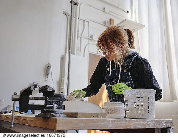 Professional female sculptor working with plaster in her studio