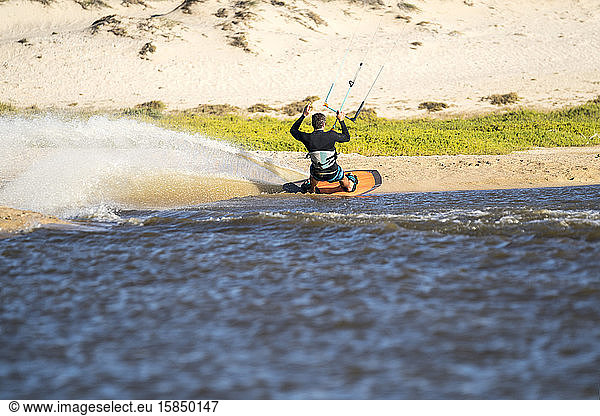 Professional male athlete kiteboarding on a sunny day in Mexico