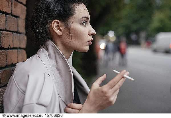 Profil einer nachdenklichen Frau mit Zigarette im Freien
