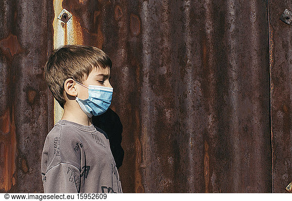 Profil eines Jungen mit Schutzmaske vor einer rostigen Wand