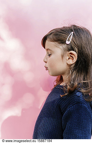 Profil eines kleinen Mädchens mit geschlossenen Augen vor rosa Hintergrund