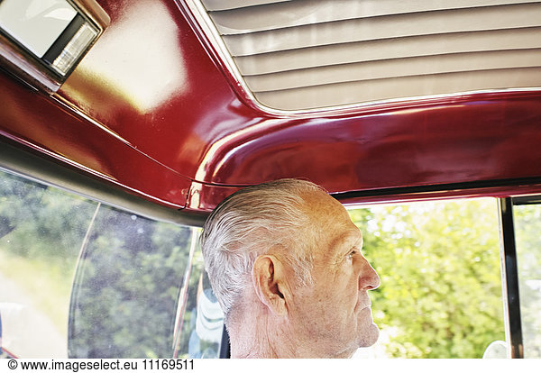 Profil eines älteren Mannes  der in einem Auto sitzt.