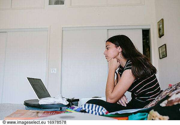 Profil eines Mädchens zwischen zwei Jahren an ihrem Laptop während der Online-Schule