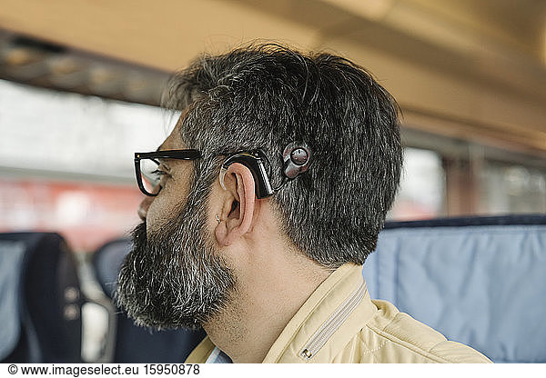 Profil eines Mannes mit Cochlea-Implantat in einem Zug