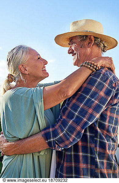 Profile happy  affectionate senior couple hugging on balcony