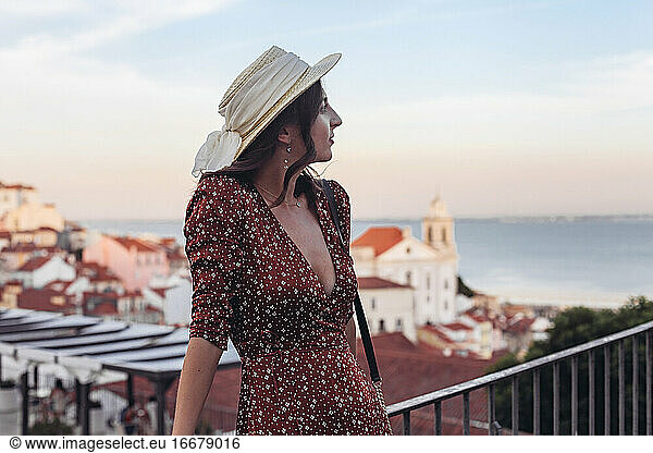 Profile of a woman in dress and a hat looking aside  sunset Lisbon