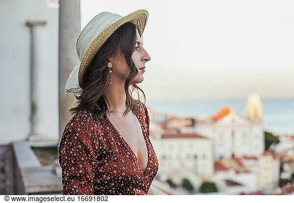 Profile of a young woman in straw hat looking over a rooftop view
