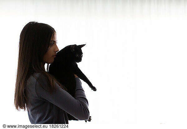 Profile Of Girl Holding Her Black Cat Inside Her Home