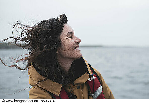 Profile of happy woman with freckles smiling on boat in Scotland