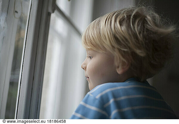 Profile of little boy looking out of window