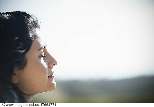Profile serene young woman basking in sunlight with eyes closed
