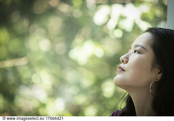 Profile serene young woman looking out window