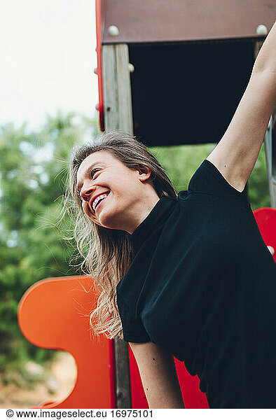 Profile Shot Of A Smiling Woman Climbing On A Swing