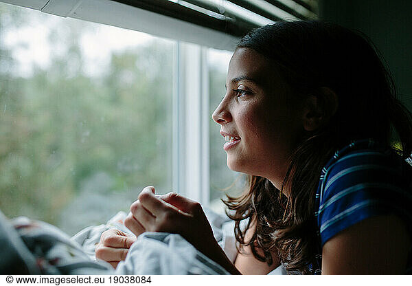 Profile shot of a tween girl looking out a window