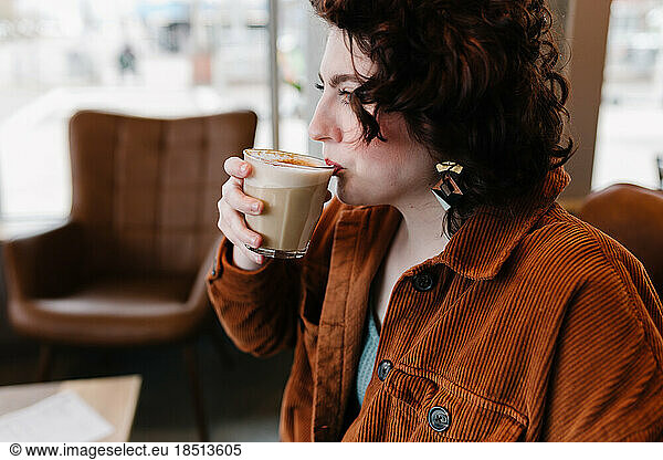 Profile view of beautiful woman taking sip of latte