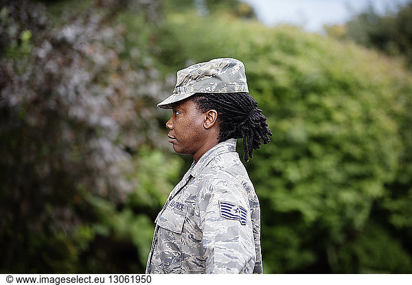 Profile view of female soldier standing against trees