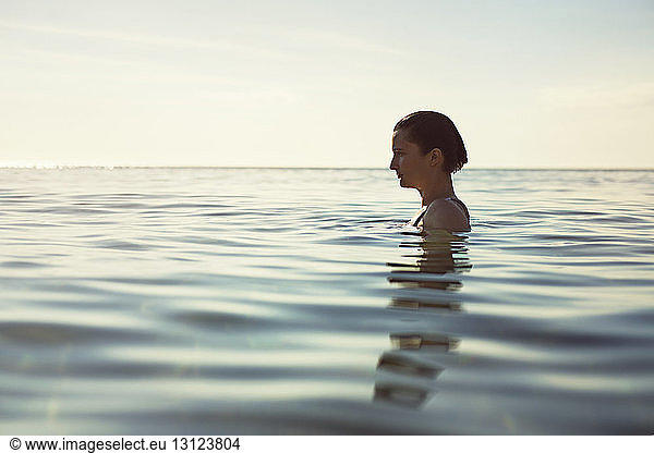 Profile view of thoughtful woman in sea against sky