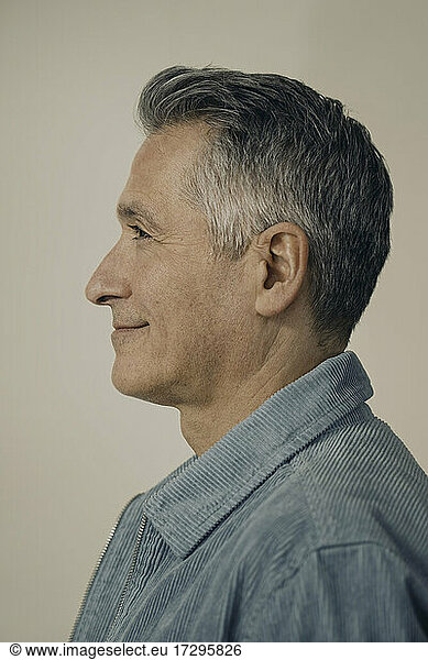 Profile view smiling mature man against beige background