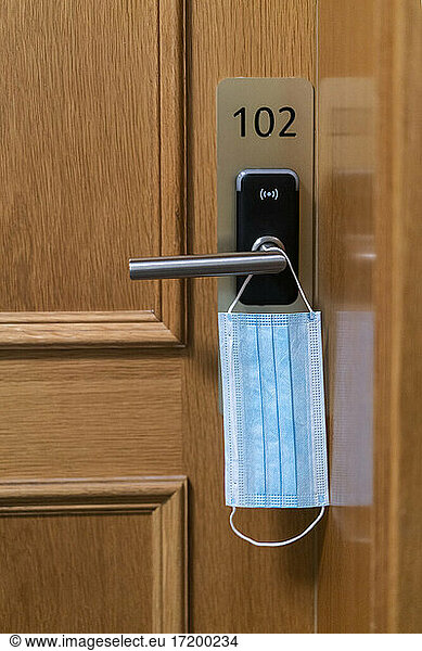 Protective face mask hanging on door lock