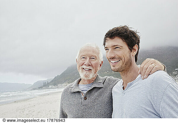 Proud father standing on the beach with his adult son