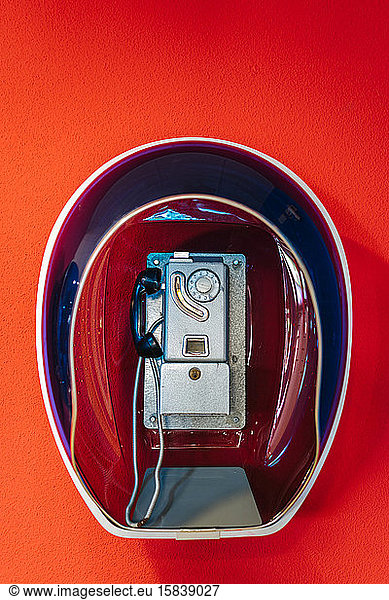 Public telephone from the seventies  hanging on a red wall