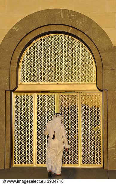 Qatari in traditioneller Tracht mit gutra  vergoldeter Westeingang  Museum of Islamic Art  nach Plänen von I. M. PEI  Abendstimmung  Corniche  Doha  Katar  Qatar  Persischer Golf  Naher Osten  Asien