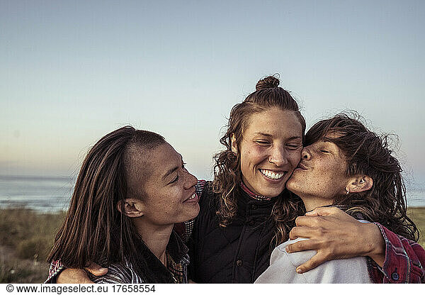 Queer alternative happy group of females hug by ocean