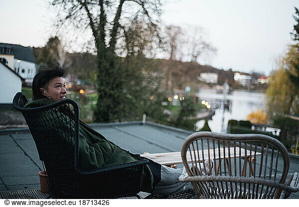 queer asian relaxes on deck at home overlooking pretty lake germany