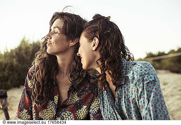 queer women couple with curls smile happily at beach in Portugal