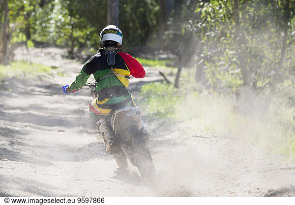 Rückansicht des jungen männlichen Motocross-Fahrers auf der Waldstrecke