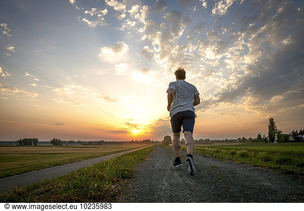 Rückansicht des Mannes beim Joggen bei Sonnenuntergang