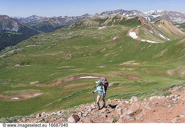 Rückansicht einer Frau beim Wandern auf einem Berg im Sommerurlaub