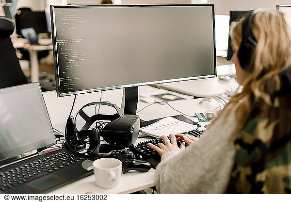 Rückansicht einer Geschäftsfrau  die im Büro am Computer arbeitet