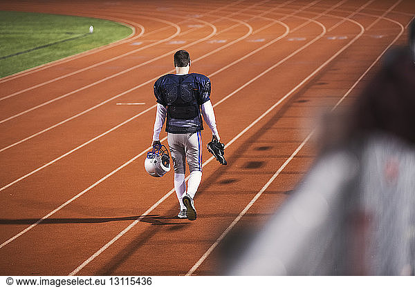 Rückansicht eines American-Football-Spielers  der auf einer Sportbahn im Stadion läuft