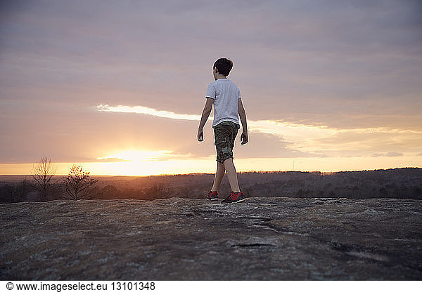 Rückansicht eines Jungen  der bei Sonnenuntergang auf dem Arabien-Berg gegen bewölkten Himmel läuft