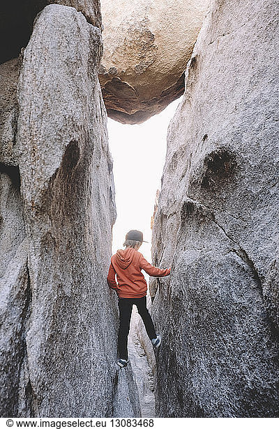 Rückansicht eines Jungen  der inmitten von Felsformationen im Joshua-Tree-Nationalpark steht