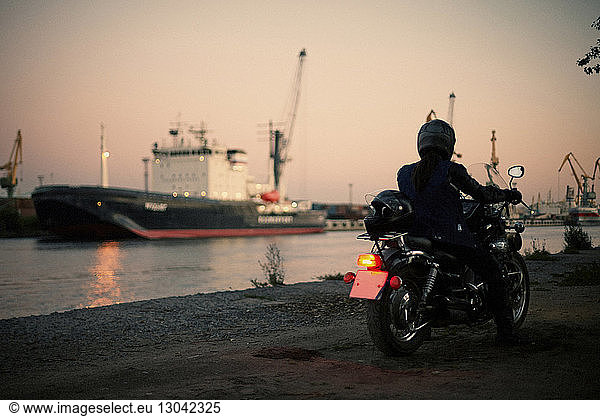 Rückansicht eines Mannes auf einem Motorrad am Dock in der Dämmerung